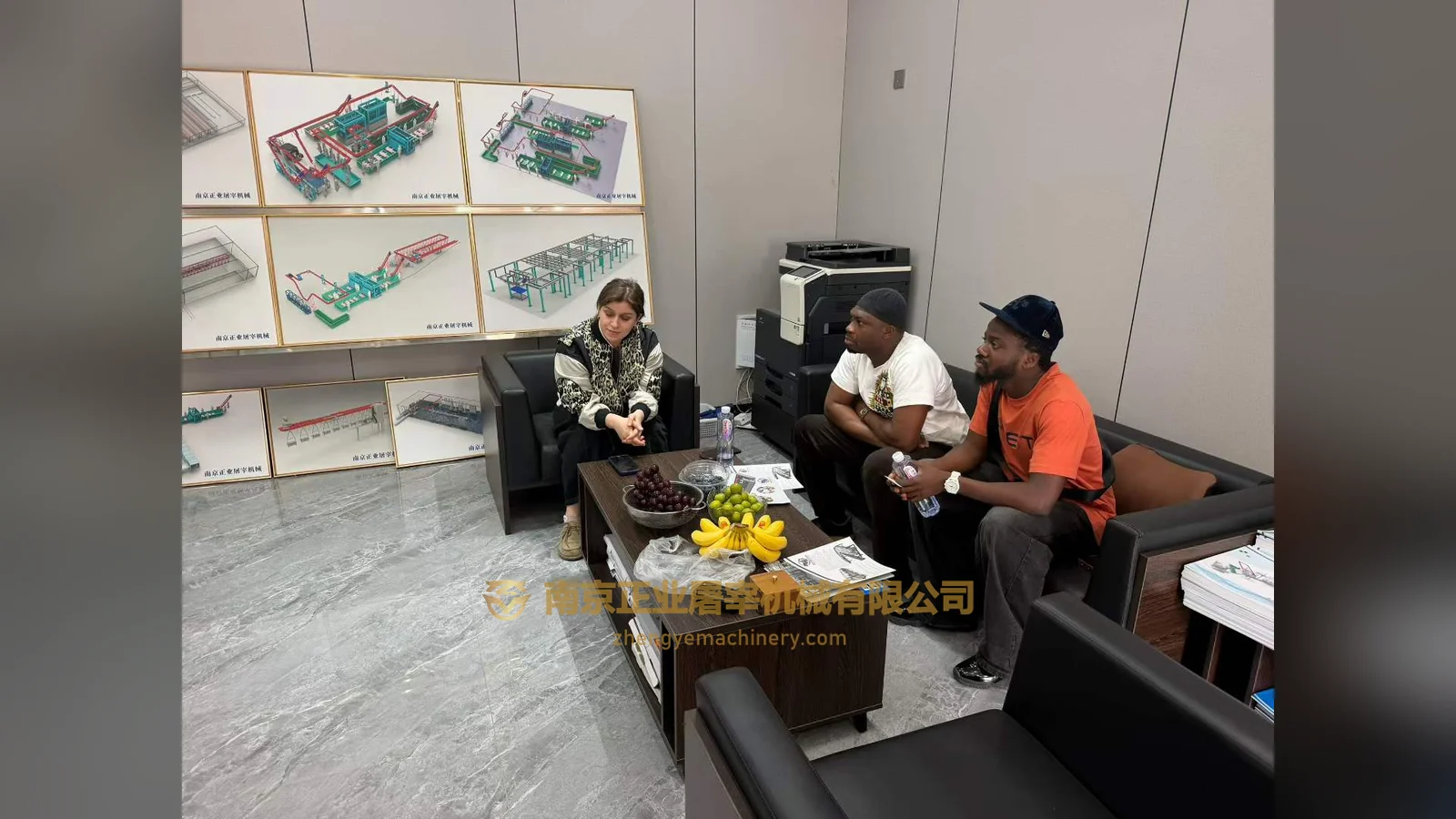 Clients from Ghana in the reception area, with production-line drawings displayed behind them